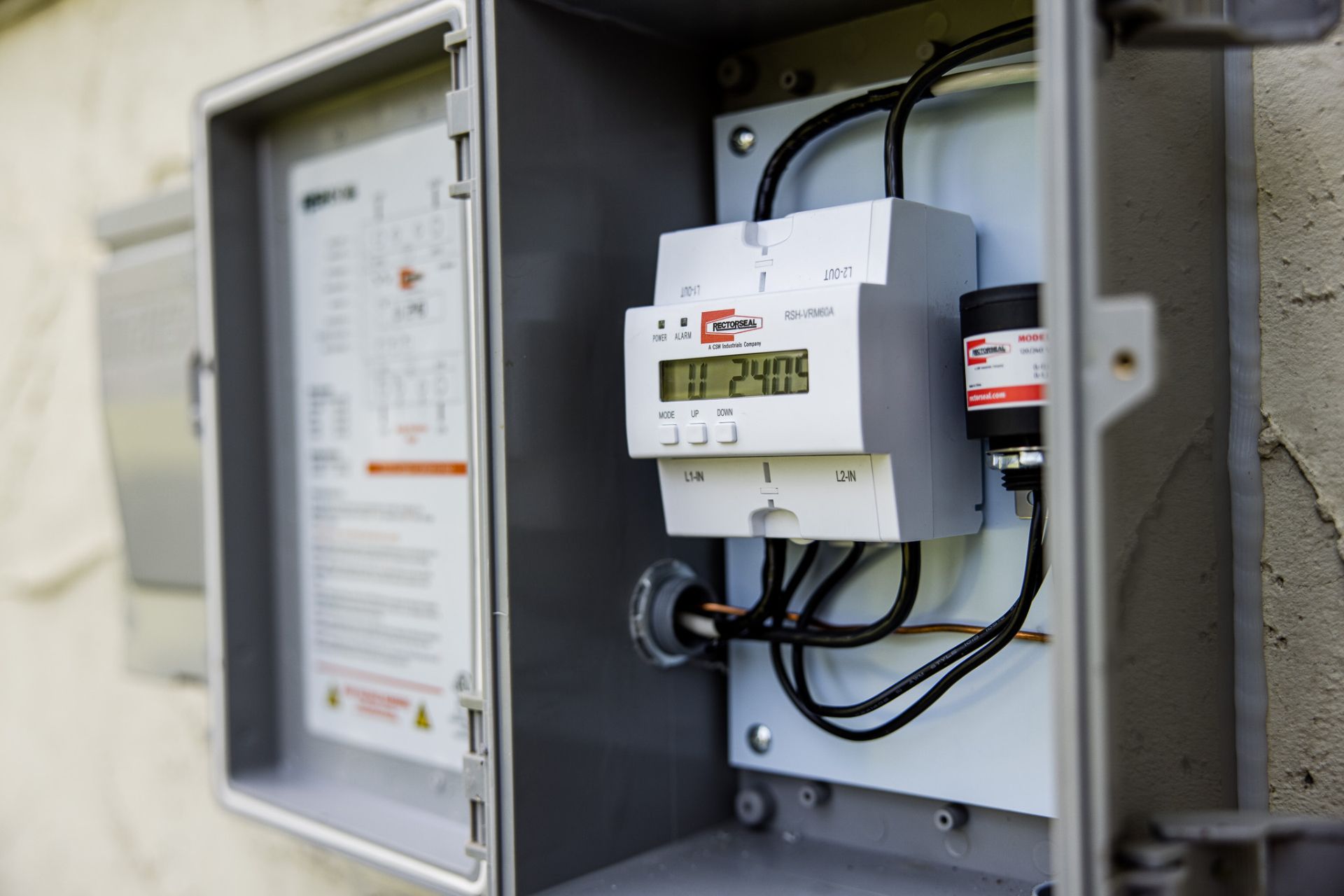 Open electrical meter panel with wiring and utility meters mounted on a wall