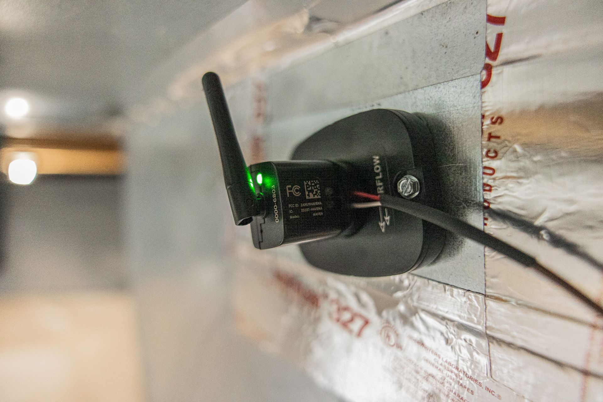 Wireless device mounted on a wall with a green indicator light and antenna