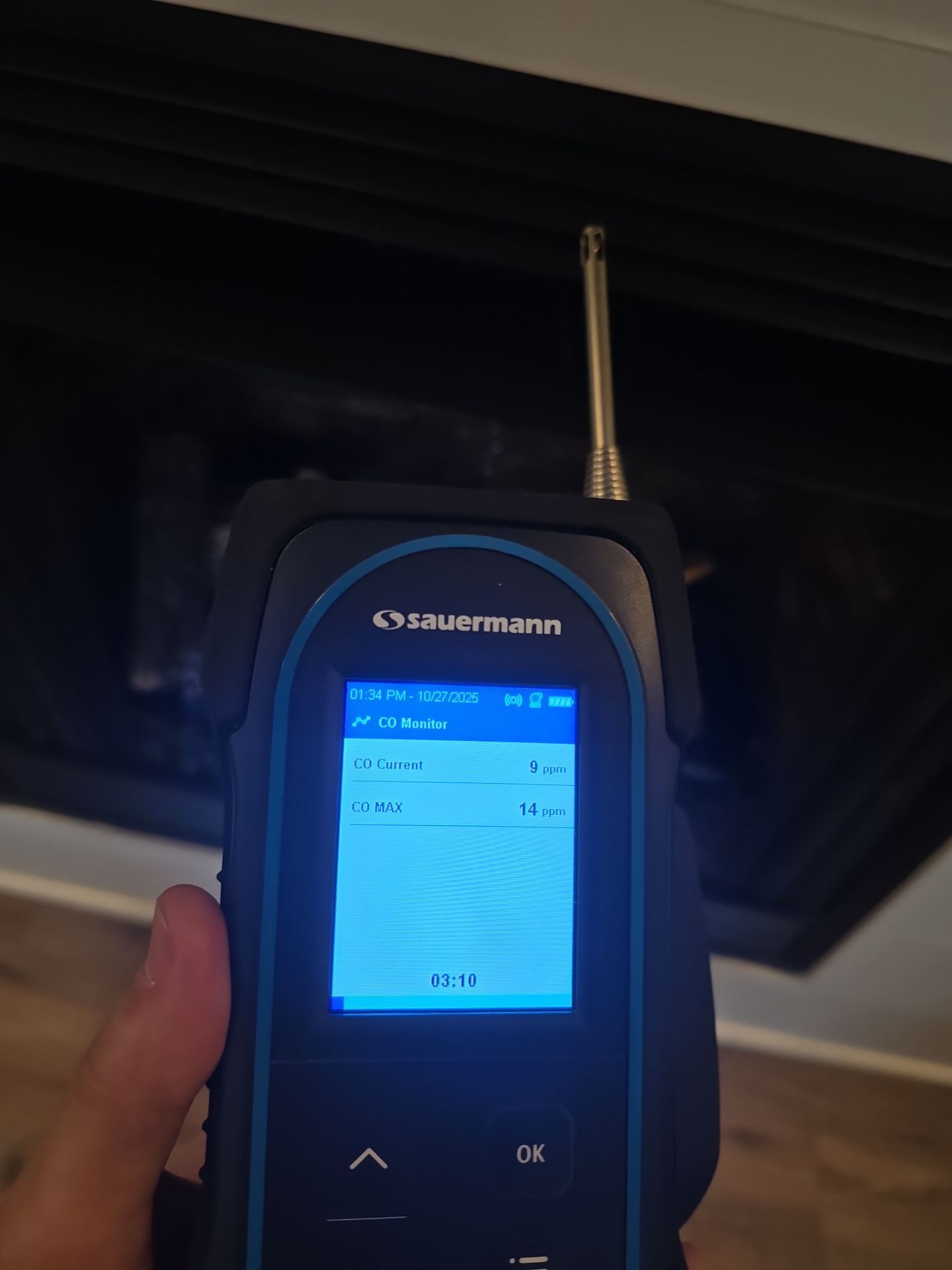 Handheld Garmin GPS device with blue screen being held up indoors