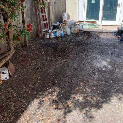 A backyard filled with buckets of paint and a ladder.