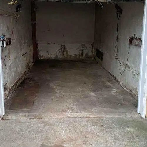 An empty garage with a concrete floor and a white door.