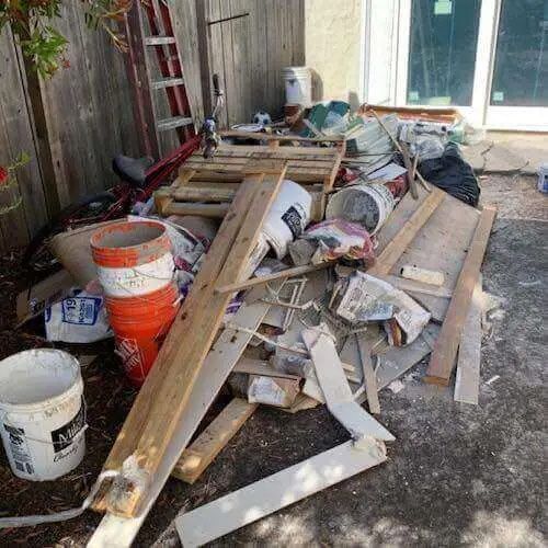 A pile of wood is sitting on the ground in a backyard.