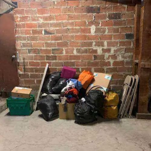 A pile of trash is sitting in front of a brick wall.