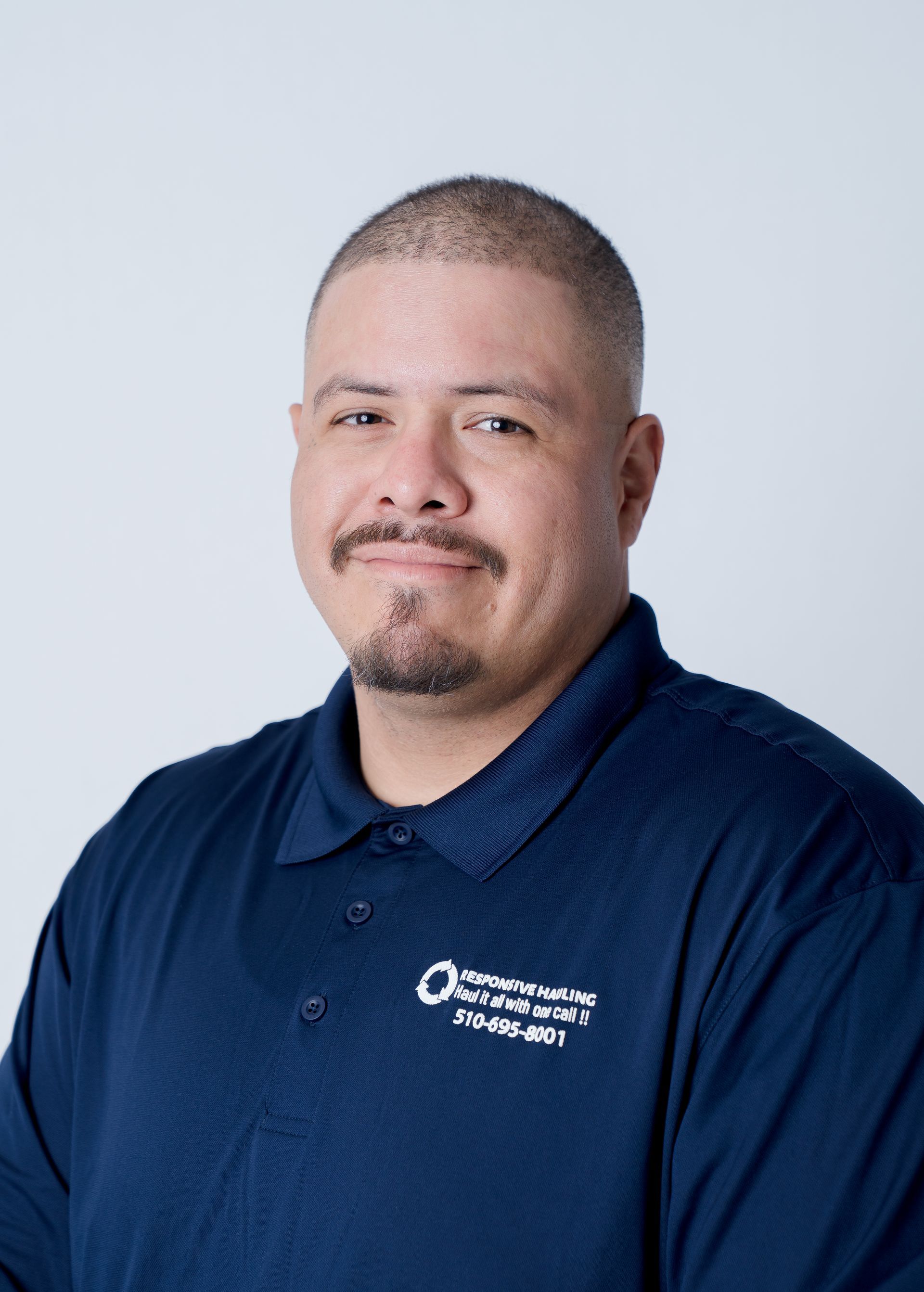 Smiling man in a navy polo with a company logo on the left chest