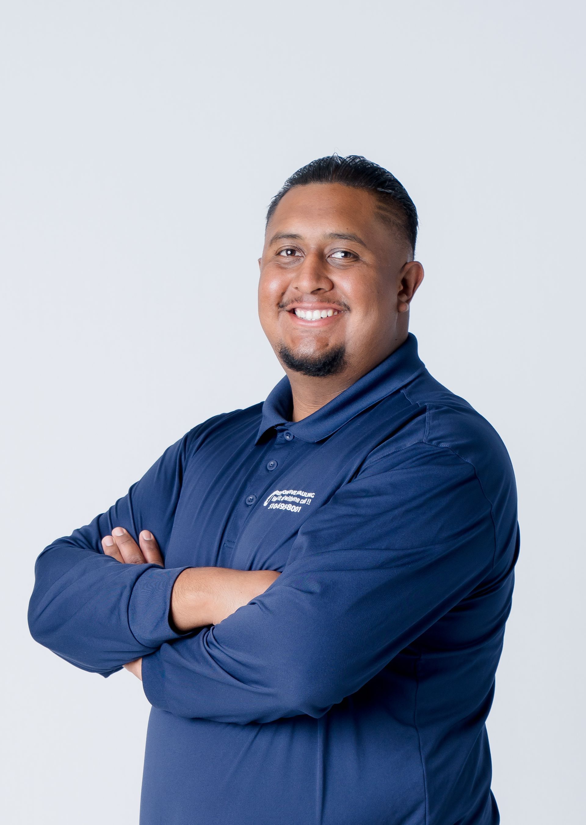 Smiling man in a navy polo with a company logo on the left chest