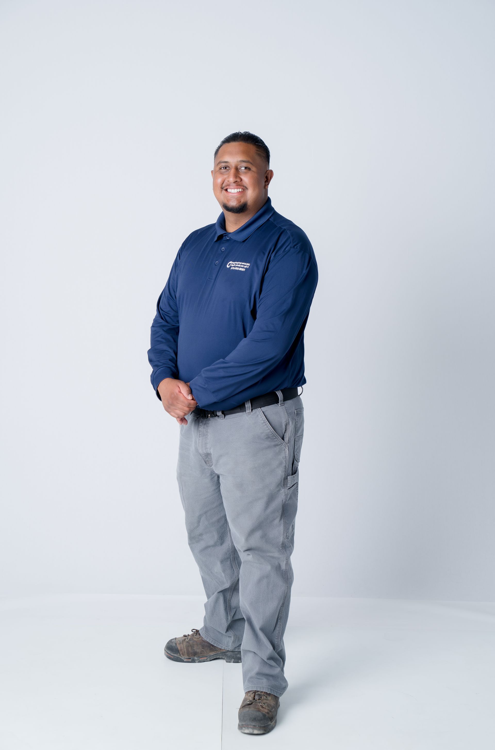 Smiling man in a navy polo with a company logo on the left chest