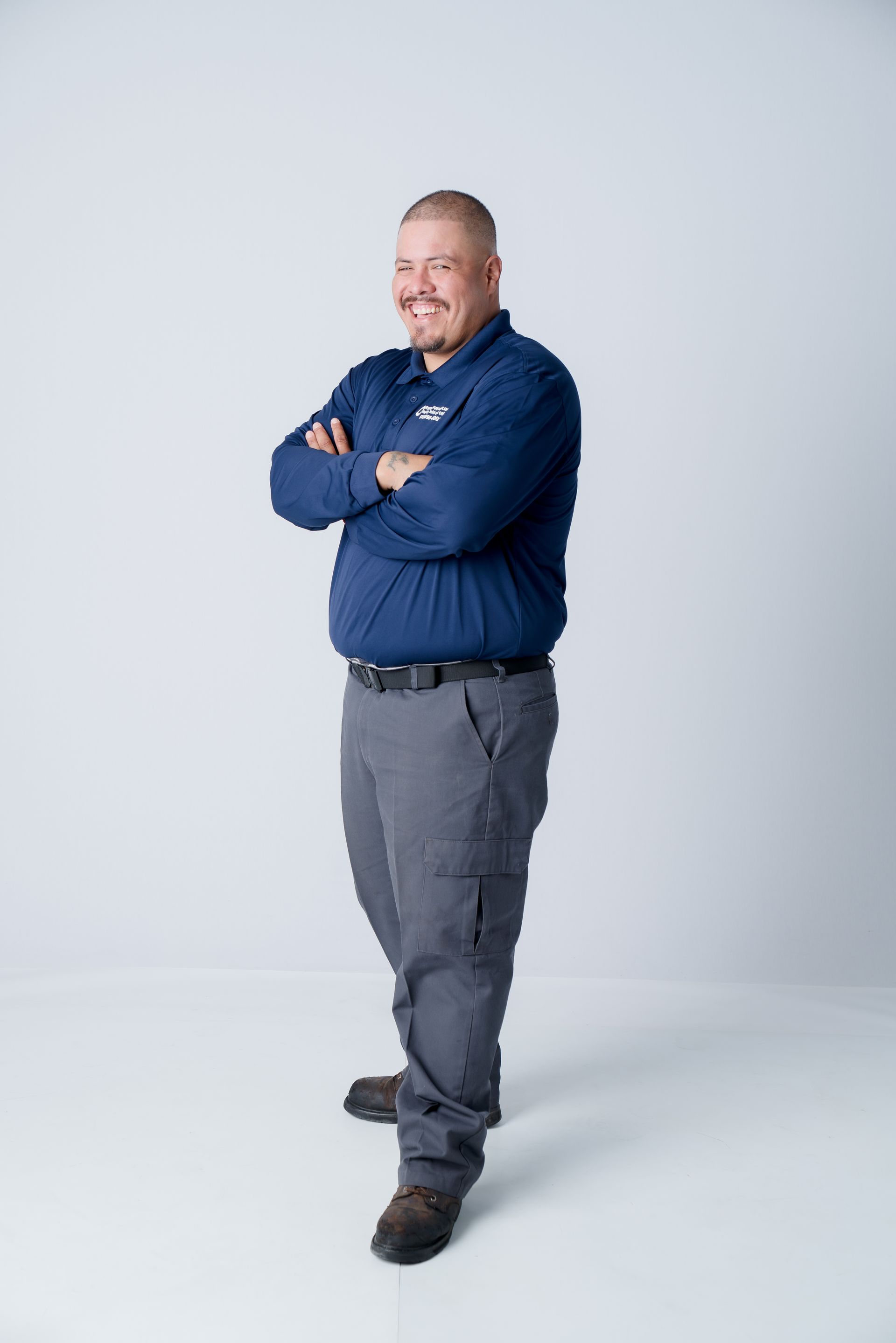 Smiling man in a navy polo with a company logo on the left chest