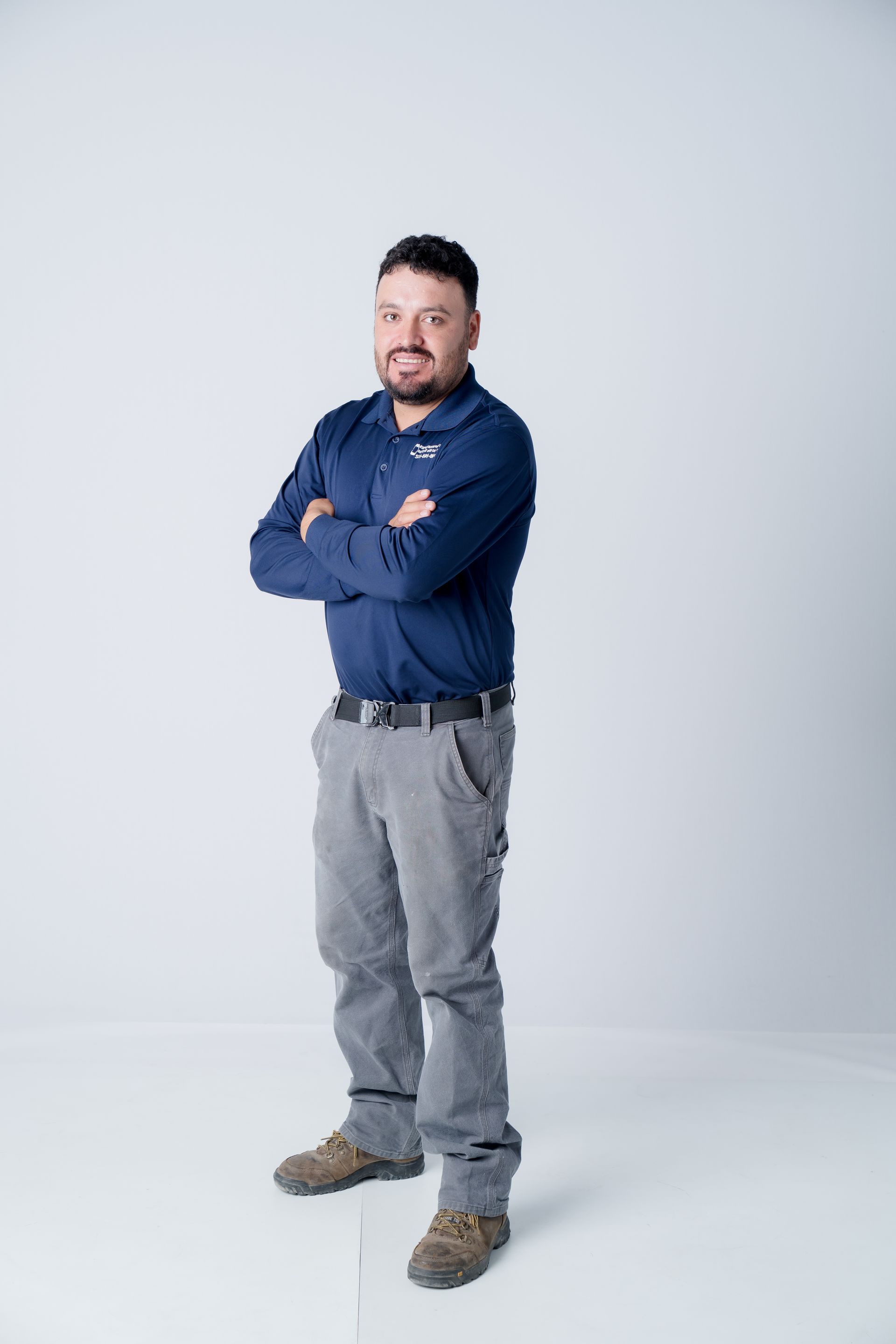 Smiling man in a navy polo with a company logo on the left chest