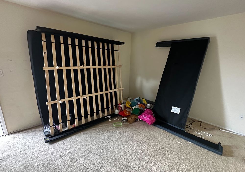 A bed frame is laying on the floor in a room.