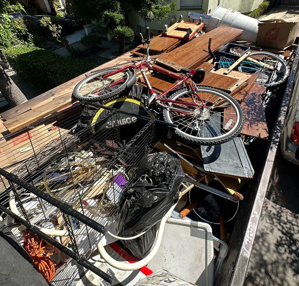 A truck full of junk with a bicycle in the back.