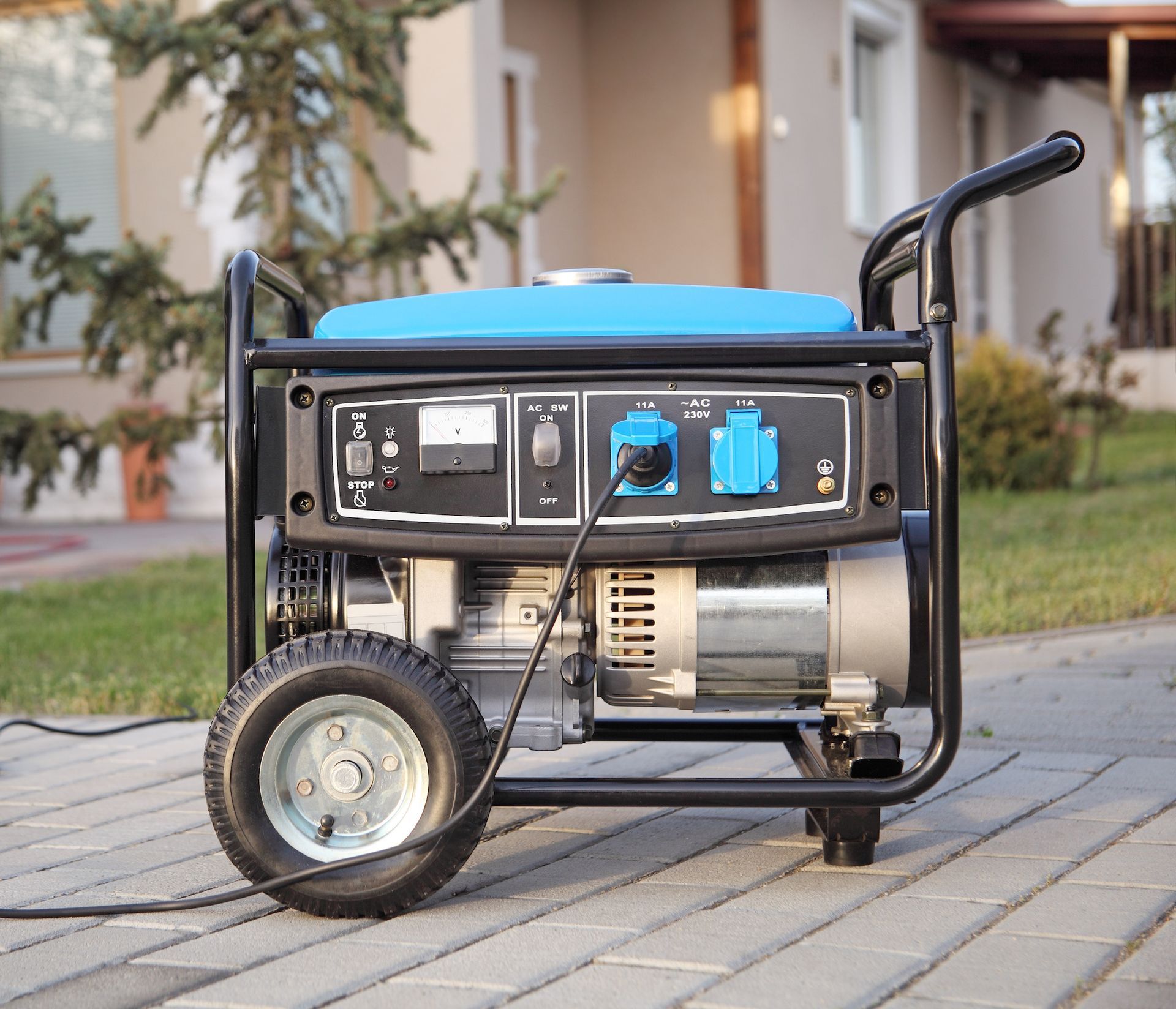 A portable generator is sitting on a sidewalk in front of a house.
