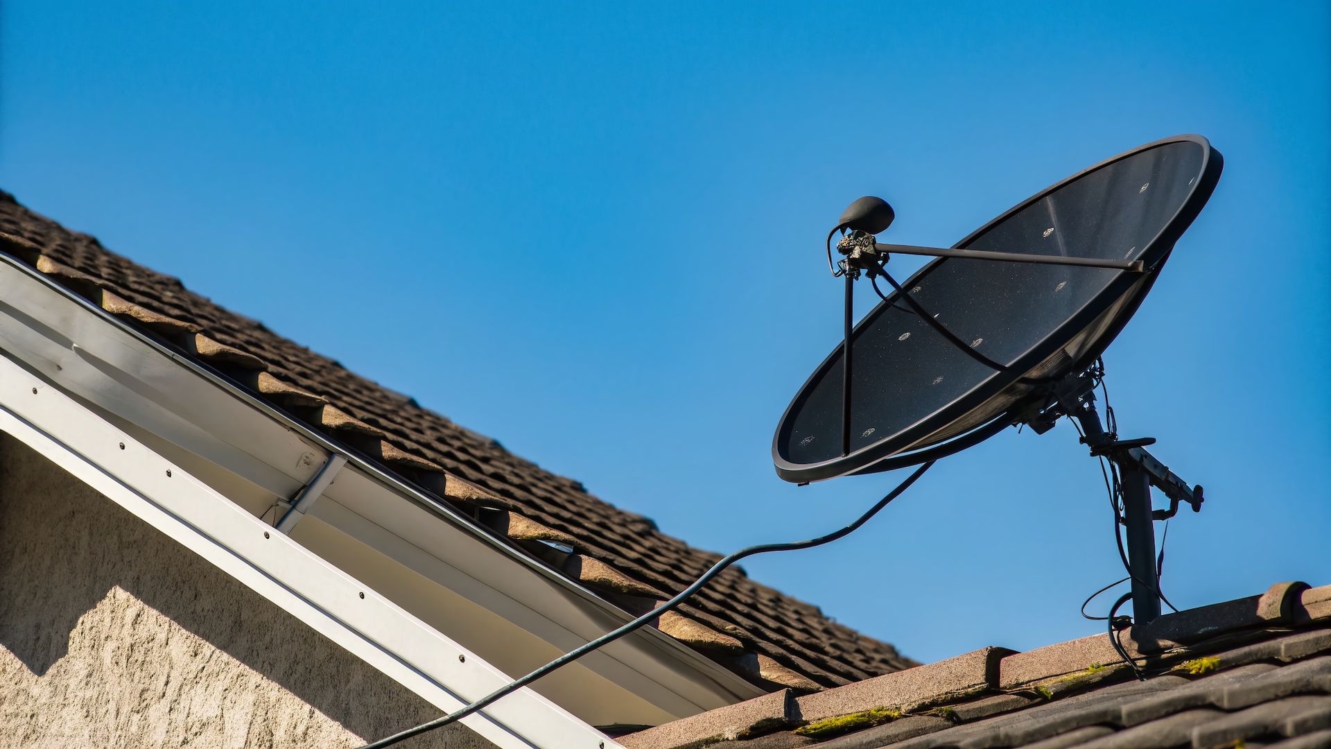 A satellite dish is mounted on the roof of a house.