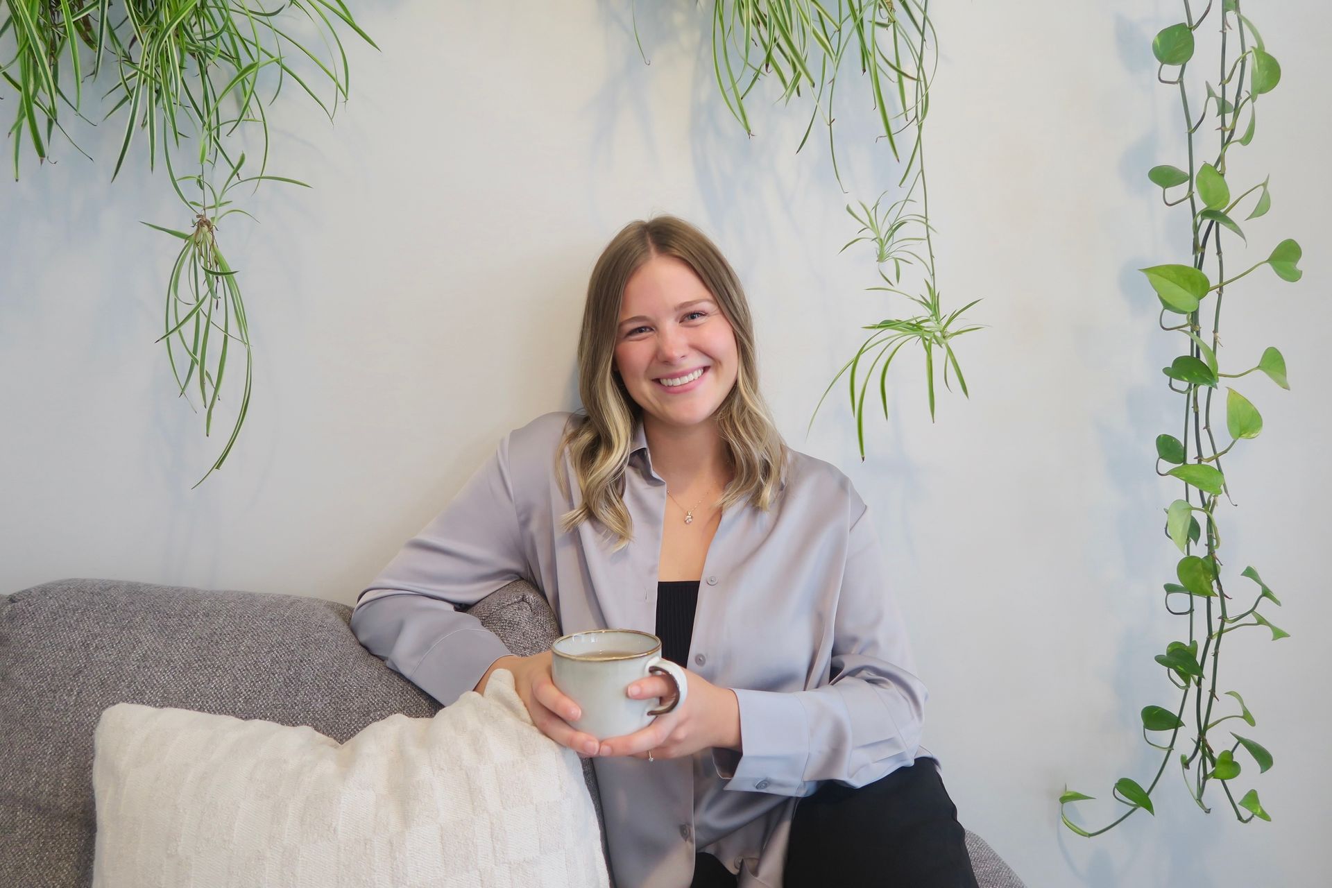 Maiah Horne smiling while sitting comfortably on a couch holding a mug.