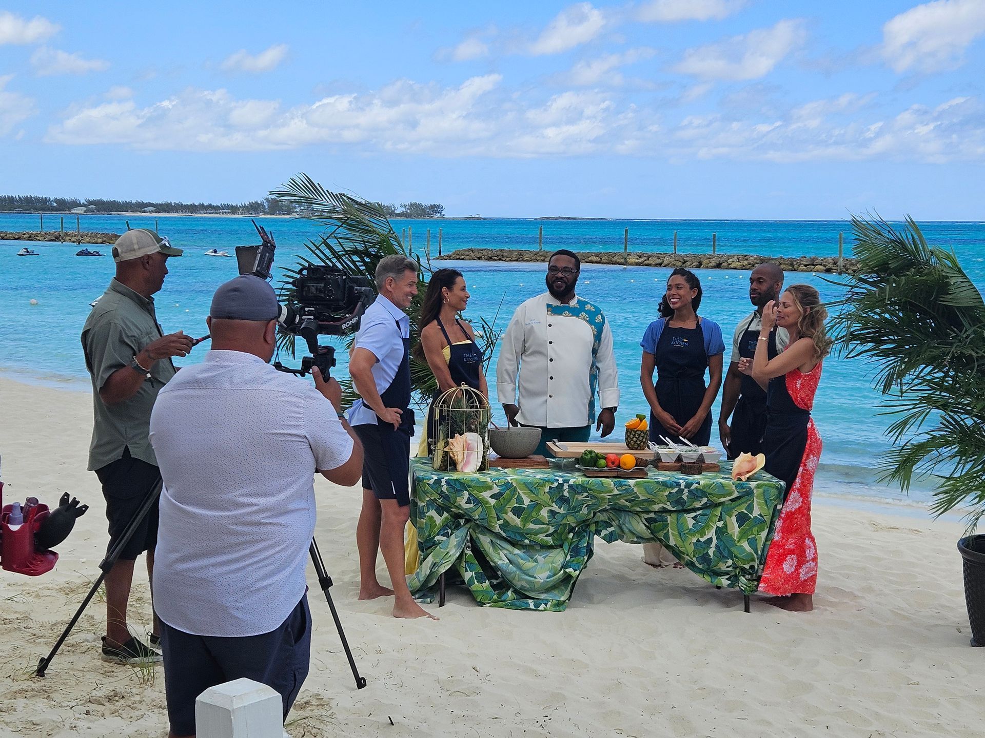 A group of people are standing around a table on the beach.