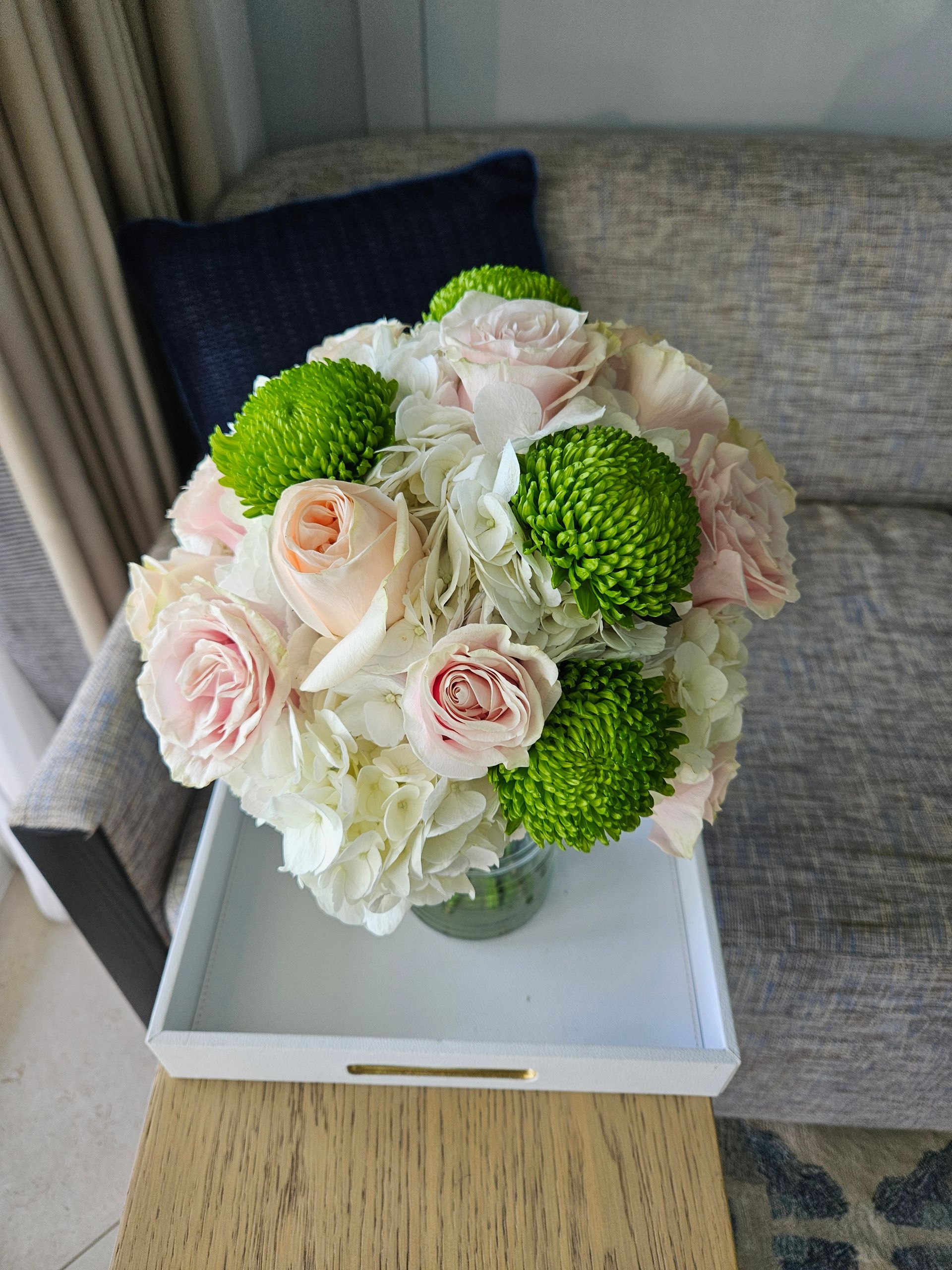 A vase filled with pink and white flowers is sitting on a table next to a couch.