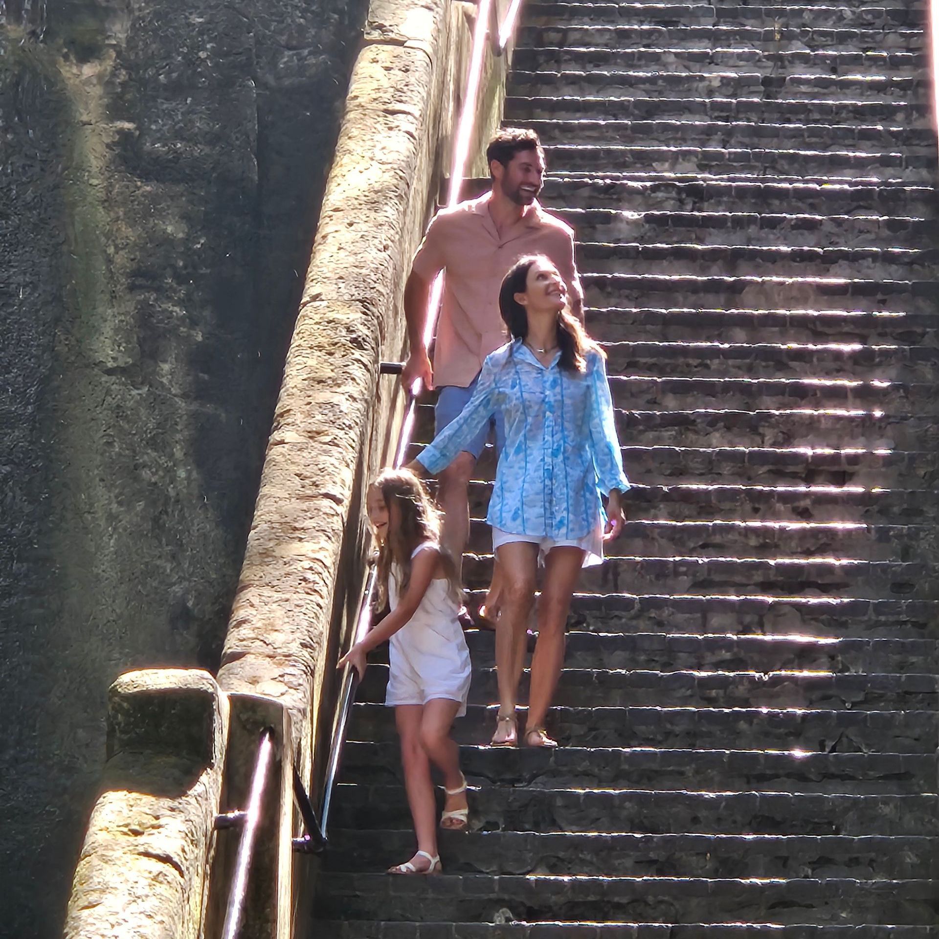 A man and two women are walking up a set of stairs