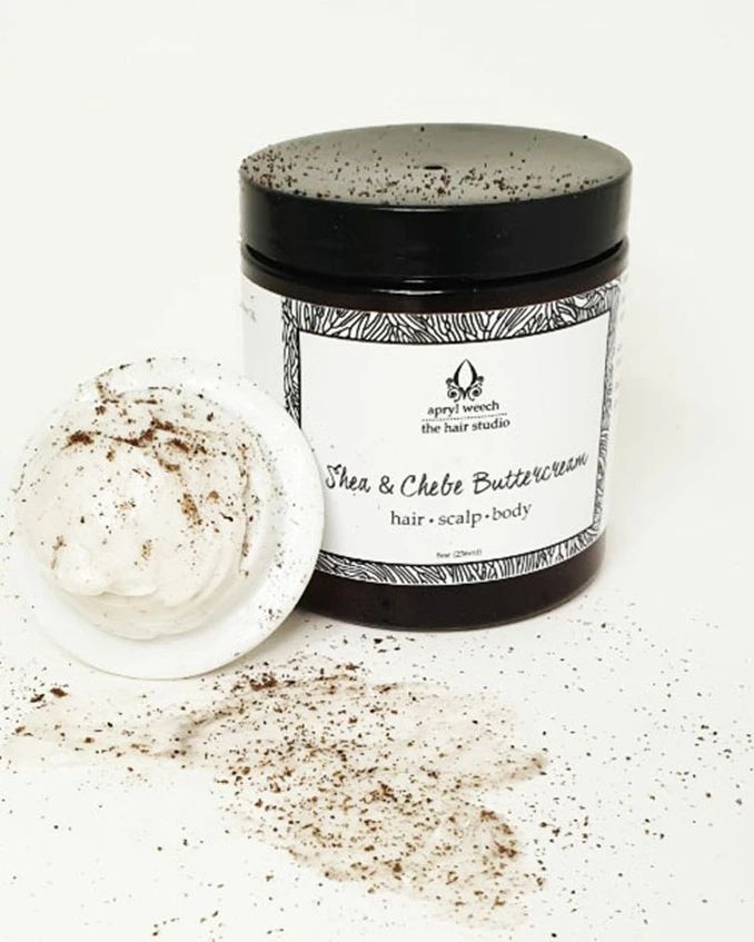A jar of shea and chebe buttercream is sitting on a table.