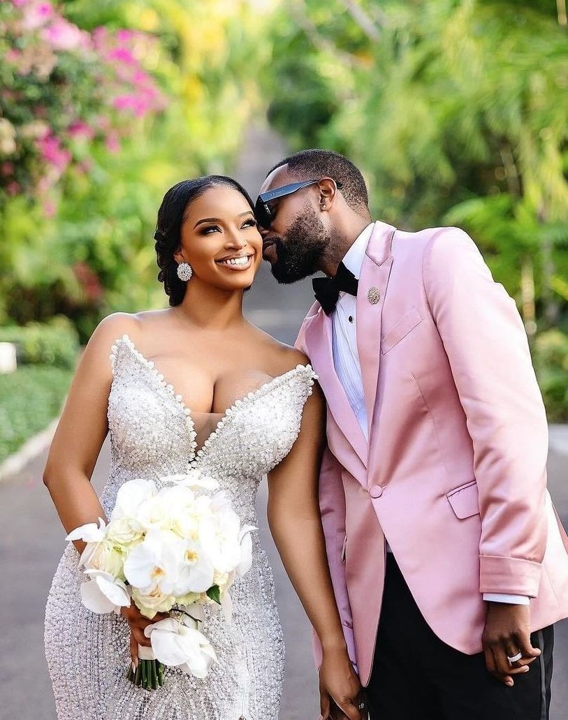 A bride and groom are kissing while standing next to each other on a road.