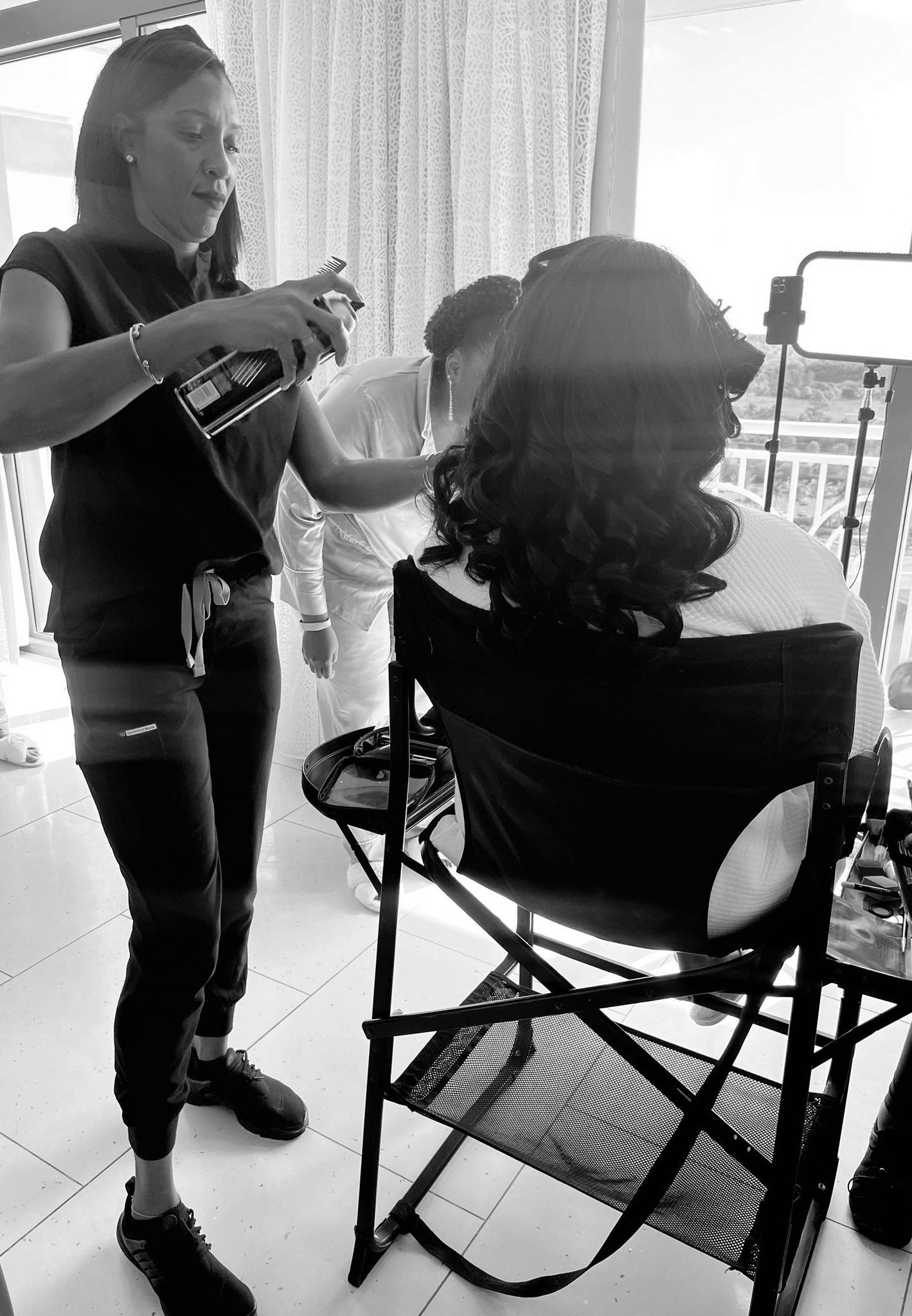 A woman is getting her hair done in a black and white photo.
