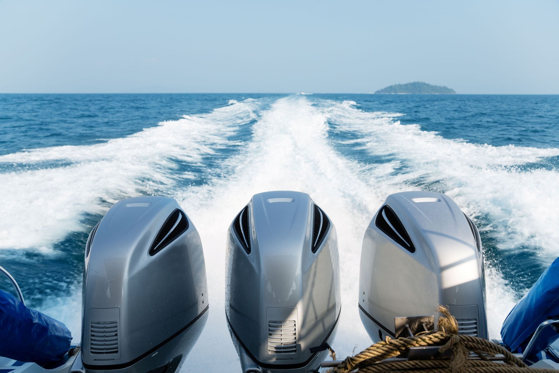 Three powerful engines mounted on a speedboat in open water.