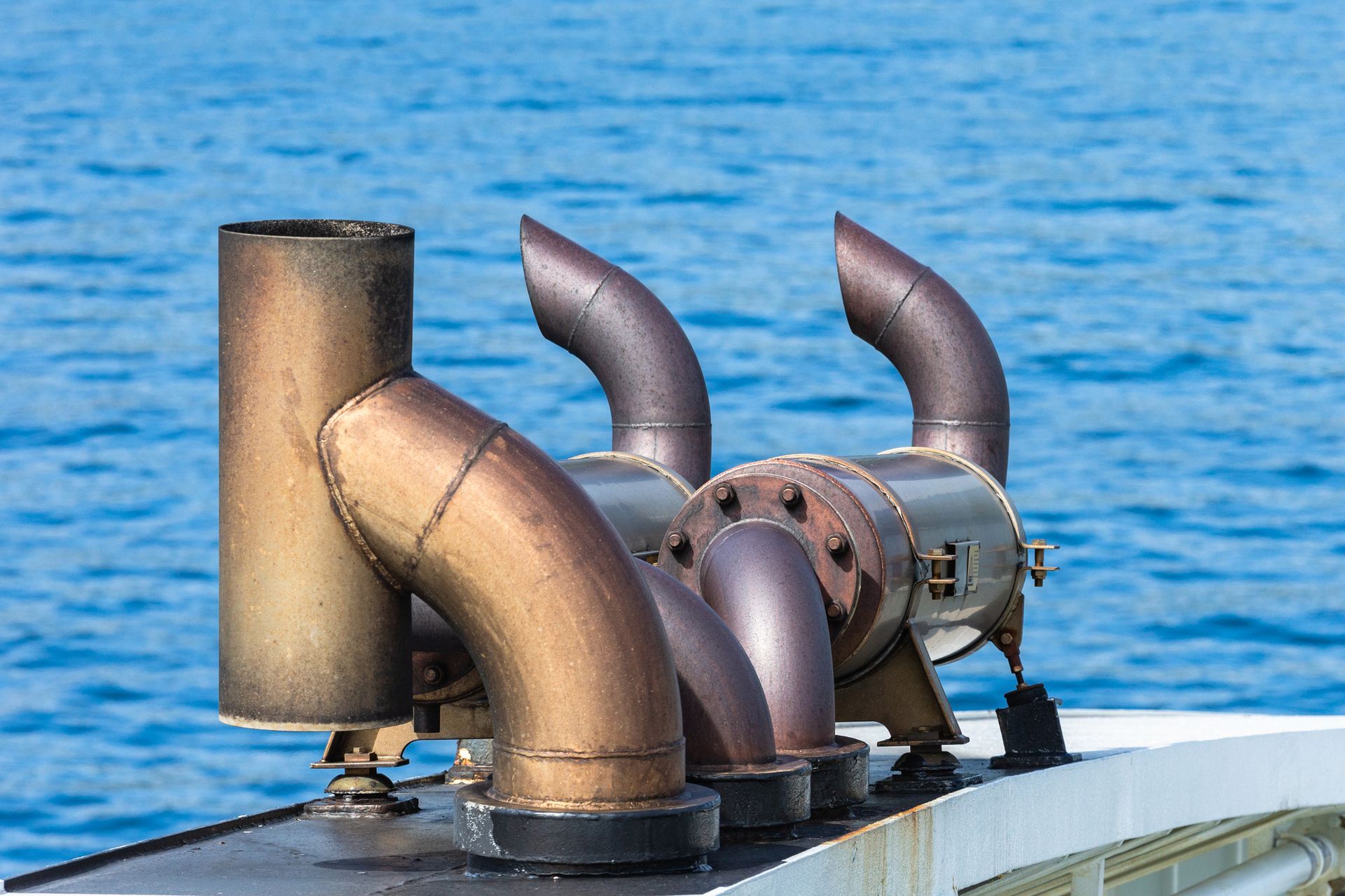 Marine exhaust systems on ferry ship with visible exhaust pipe emitting steam.