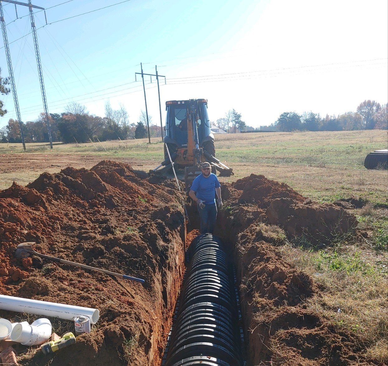 Man working on construction with excavator behind him — Grovetown, GA — Burnley Sanitary Sewer & Drain Service LLC