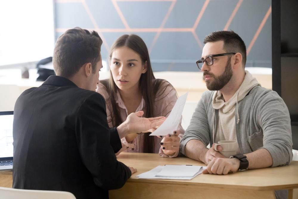 A Lawyer Discusses Something with a Concerned Couple at a Desk.