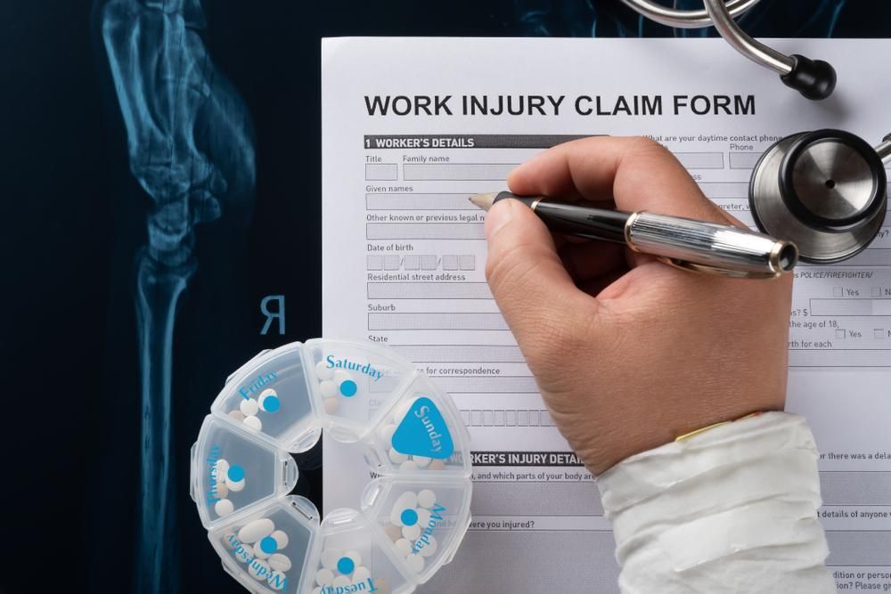 A Person is Writing on a Work Injury Claim Form — Tony Love Lawyers in Byron Bay, NSW