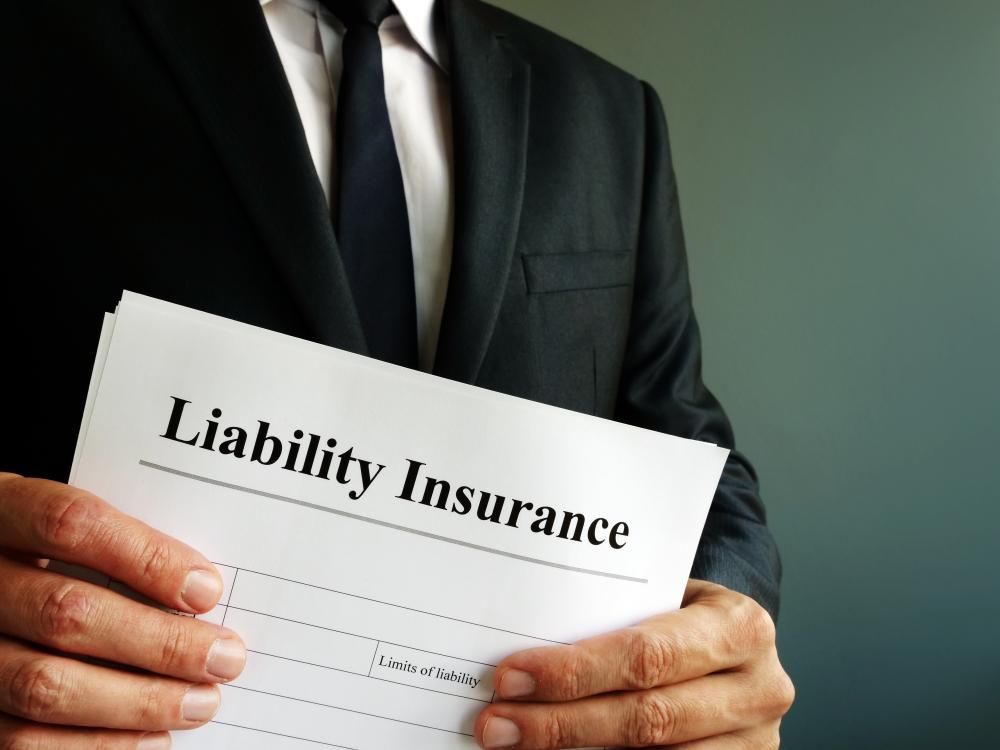 A Man in a Suit and Tie is Holding a Liability Insurance Form — Tony Love Lawyers in Lismore, NSW