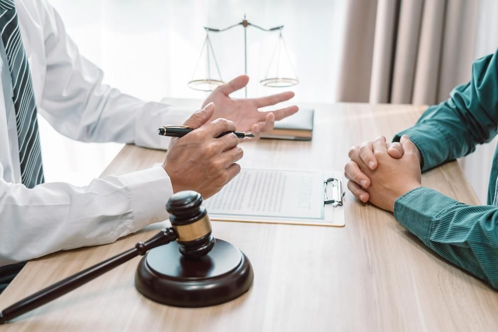 A Lawyer is Talking to a Client While Sitting at a Table With a Gavel — Tony Love Lawyers in Lismore, NSW