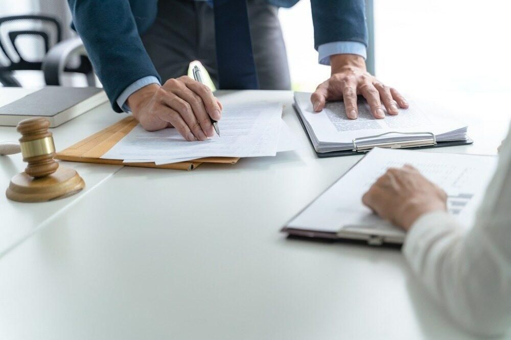A Man and a Woman Are Sitting at a Table With Papers and a Gavel — Tony Love Lawyers in Ballina, NSW