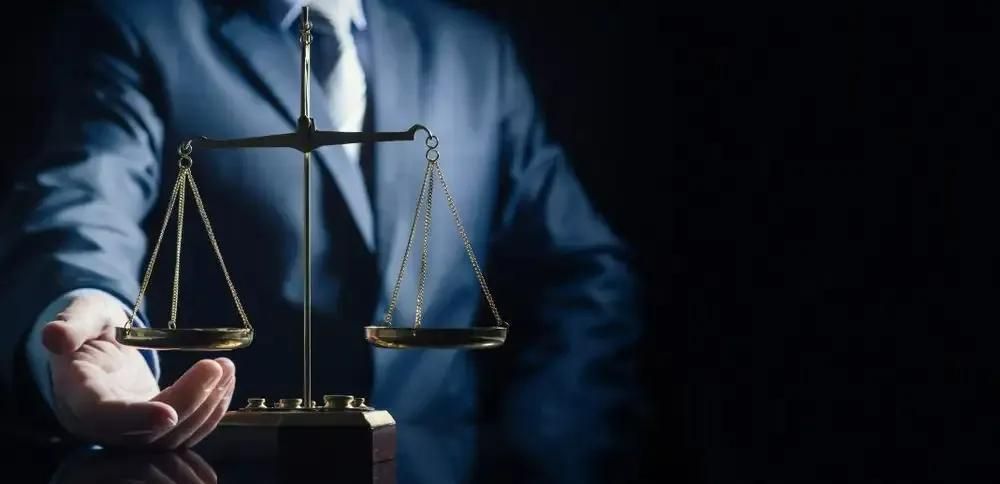 A Man in a Suit and Tie is Holding a Scale of Justice in His Hand — Tony Love Lawyers in Tweed Heads, NSW