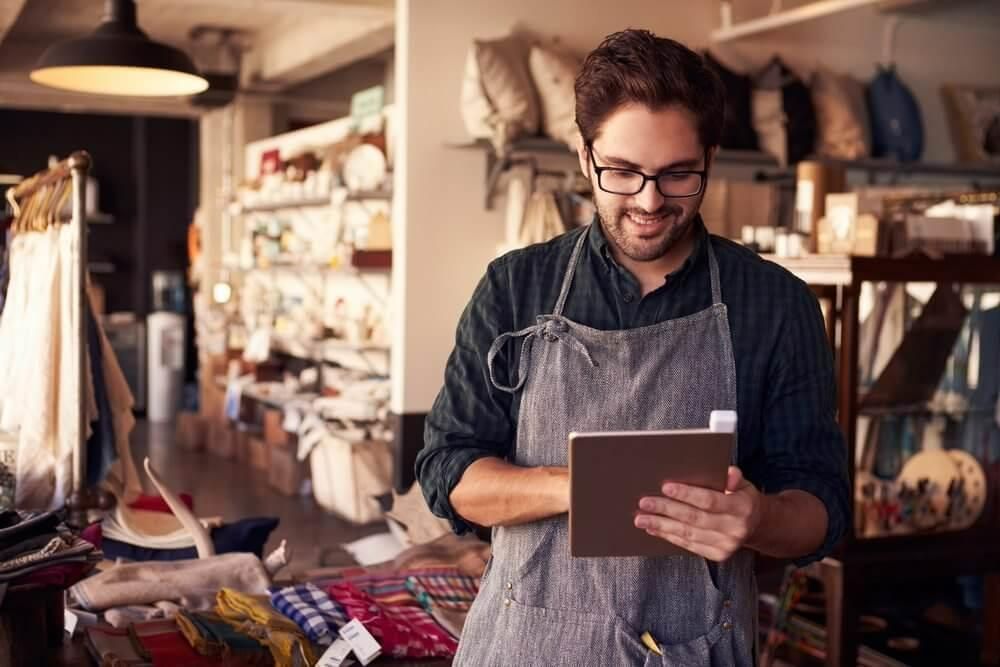 A Man in an Apron is Using a Tablet Computer in a Store — Tony Love Lawyers in Lismore, NSW