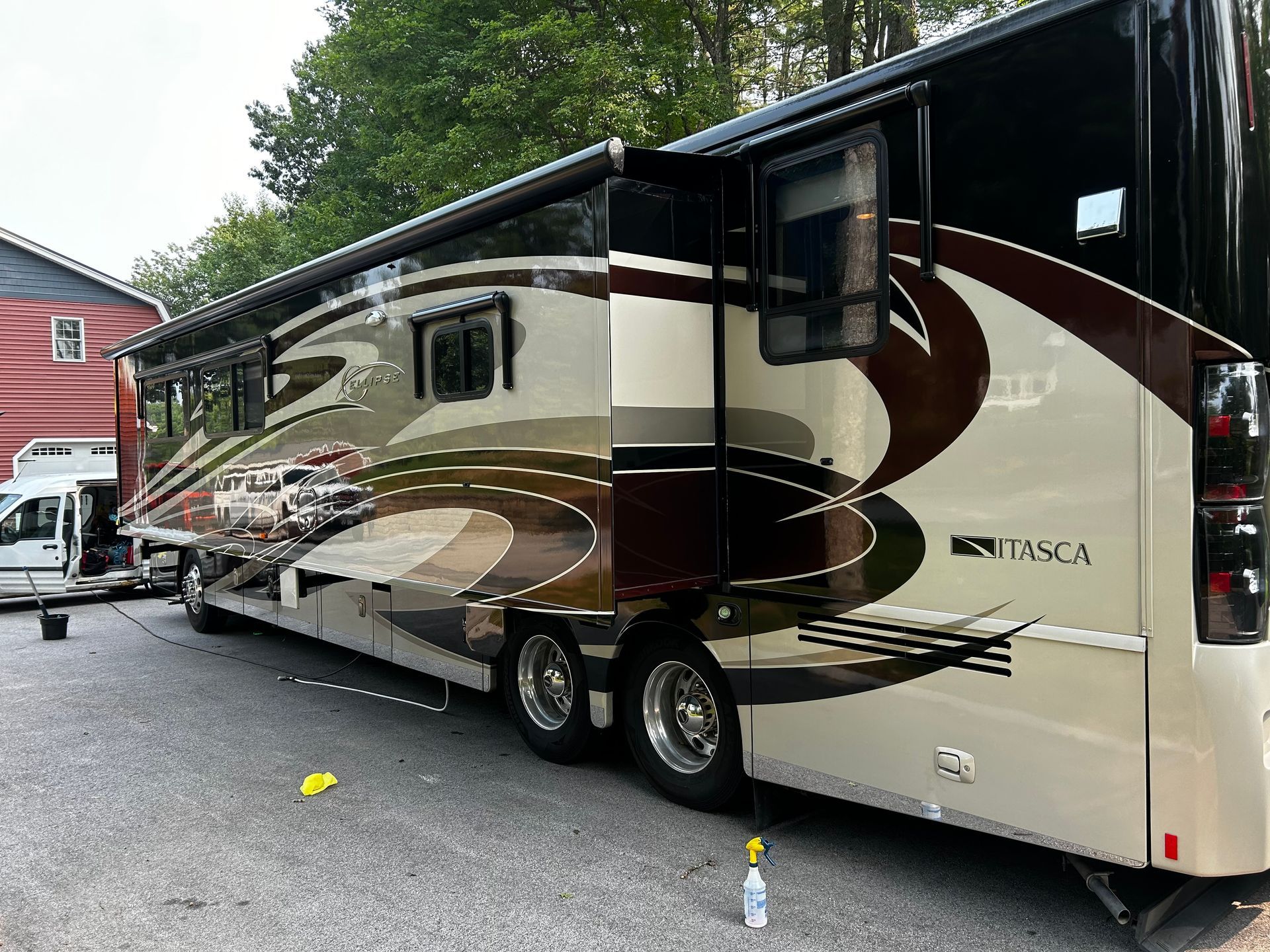 A large, luxury RV with a brown and tan paint scheme is parked outside on a paved area.