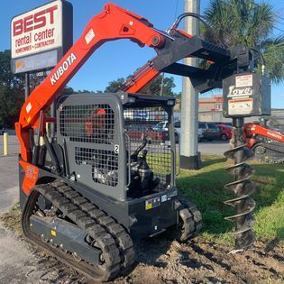 A small tractor is parked in front of a best rental center sign.