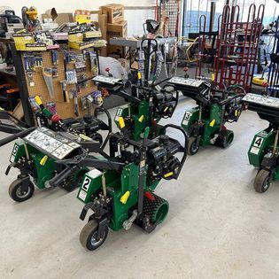 A bunch of green carts are lined up in a room.