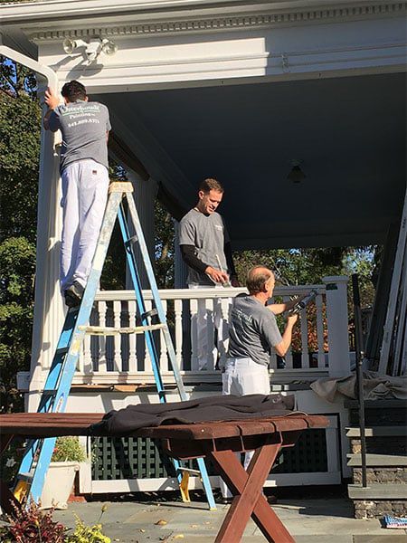 family crew photo of them working on painting a porch
