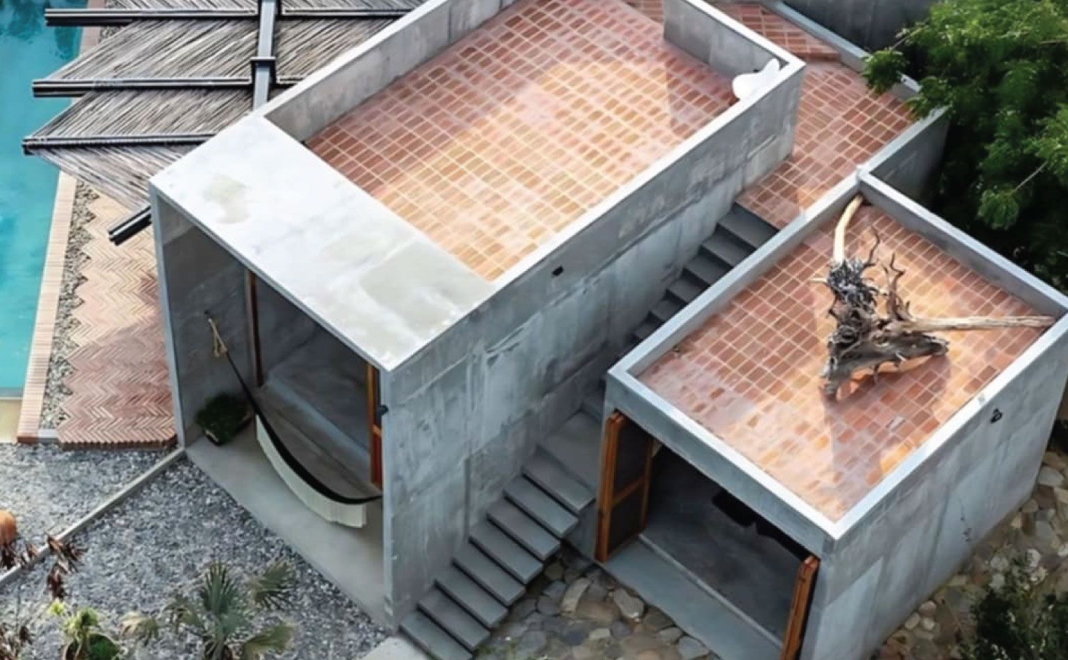 Modern concrete house with pool. Flat tile roofs, stone patio, hammock, and stairway.