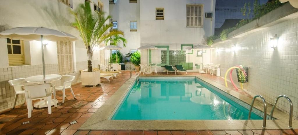 Uma grande piscina com mesas e cadeiras ao redor.