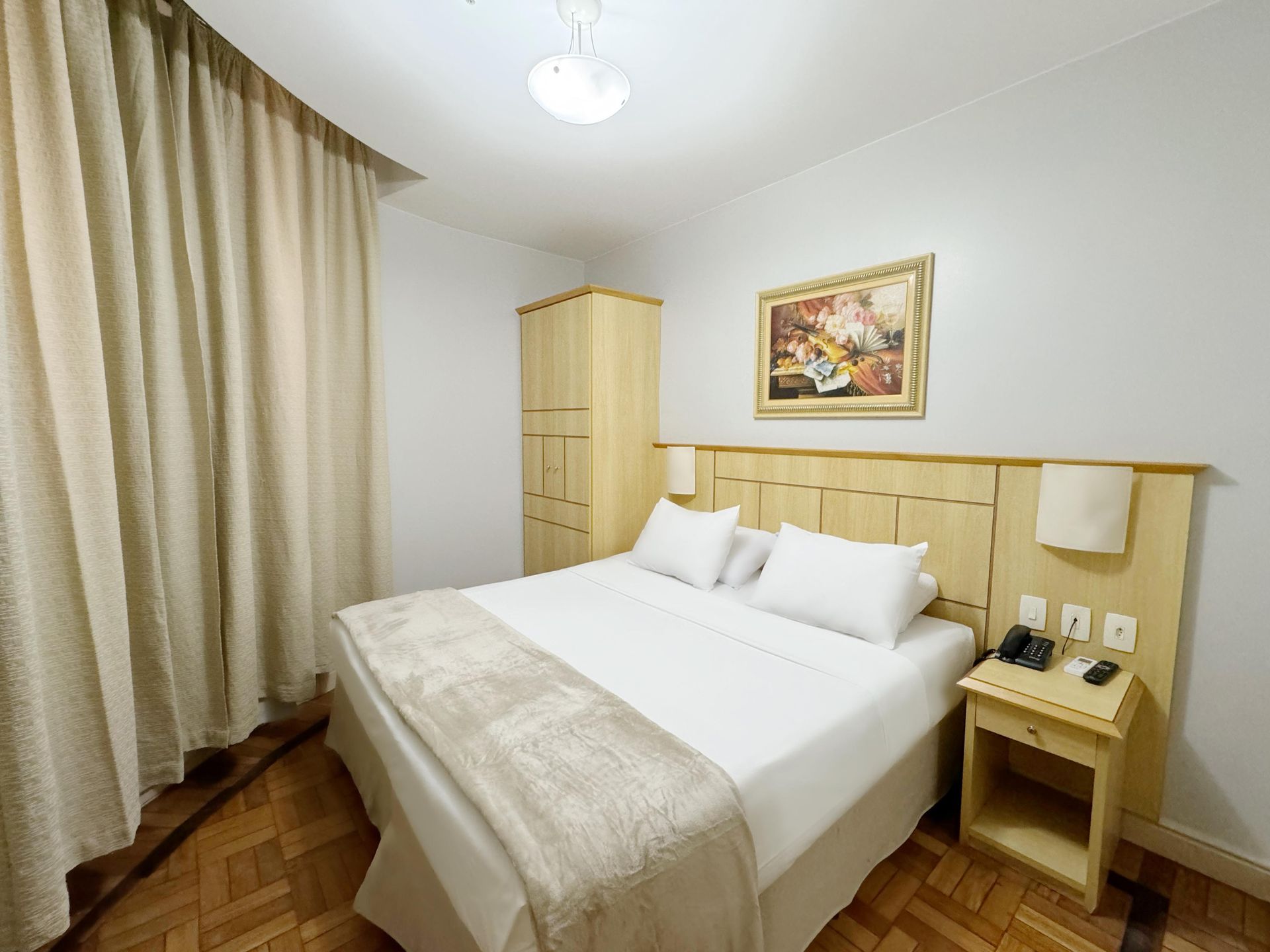 Um quarto de hotel com uma cama king size e uma mesa de cabeceira.