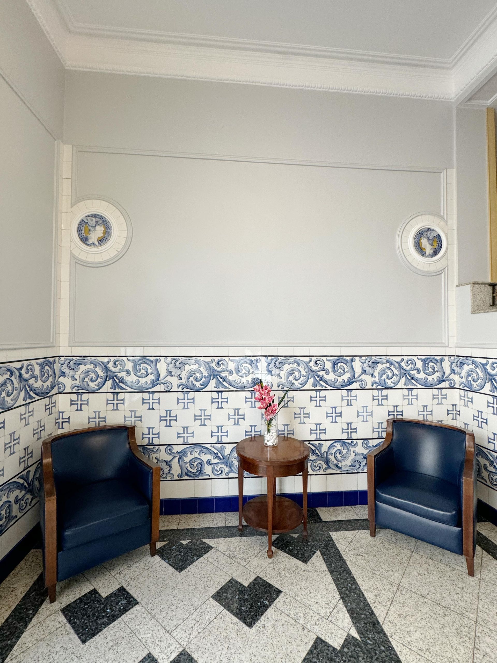 Uma sala com duas cadeiras e uma mesa com um vaso de flores sobre ela.