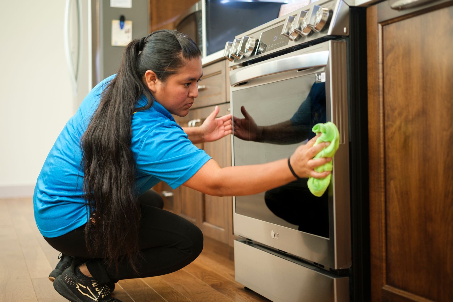 Person cleans oven with a green cloth in a kitchen.