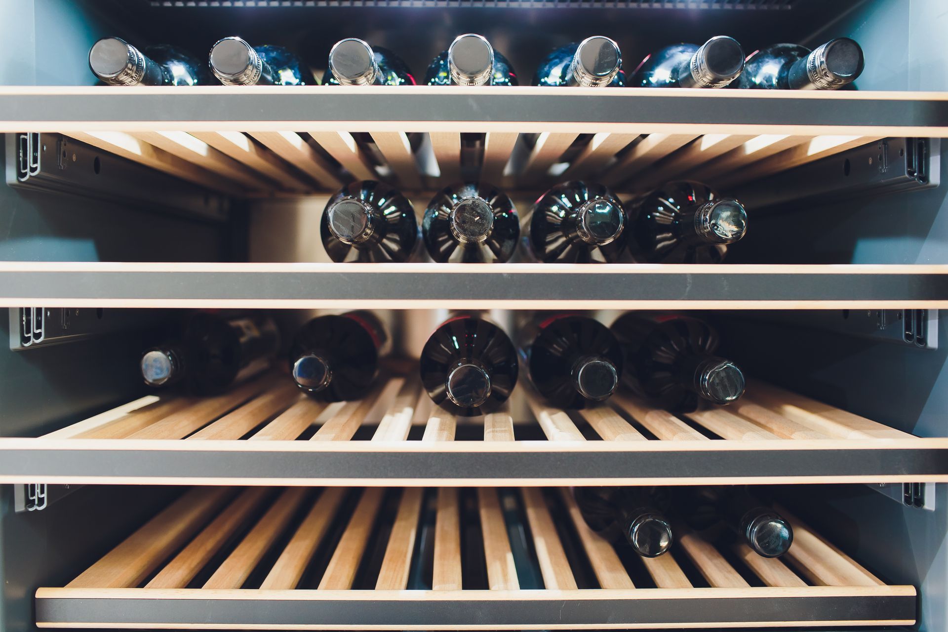 Wine bottles stored on wooden racks in a dimly lit cellar cabinet Wine bottles stored on wooden racks in a dimly lit cellar cabinet