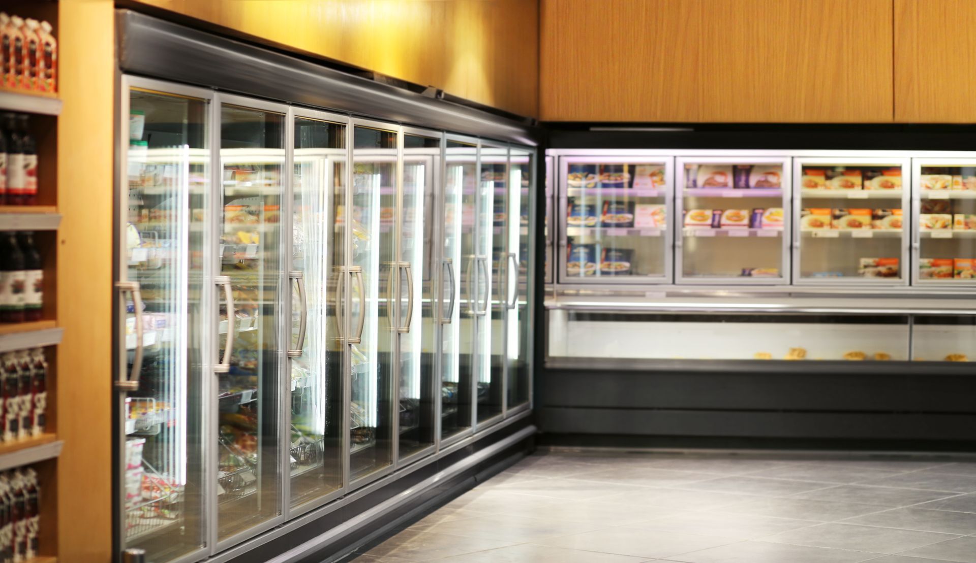 Empty supermarket refrigerated aisle with glass-door freezers and warm wood-paneled walls Empty supermarket refrigerated aisle with glass-door freezers and warm wood-paneled walls
