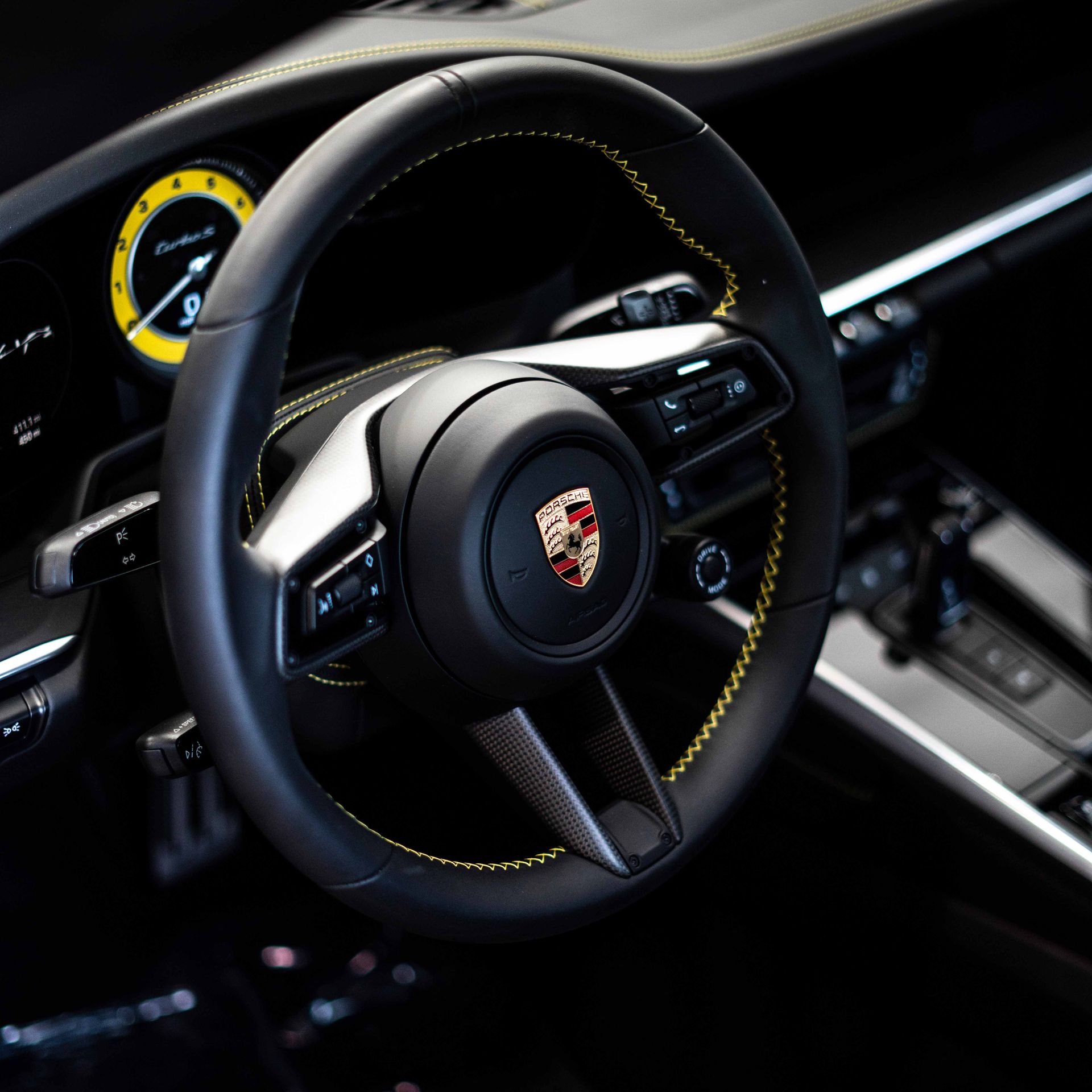 A close up of a porsche steering wheel in a car