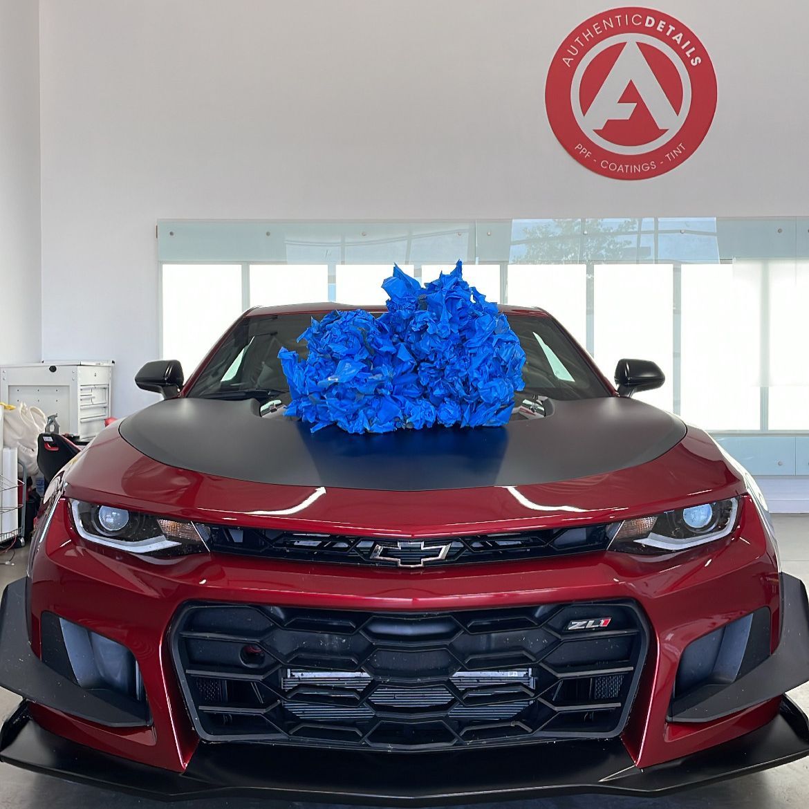 A red car with a bunch of blue flowers on the hood