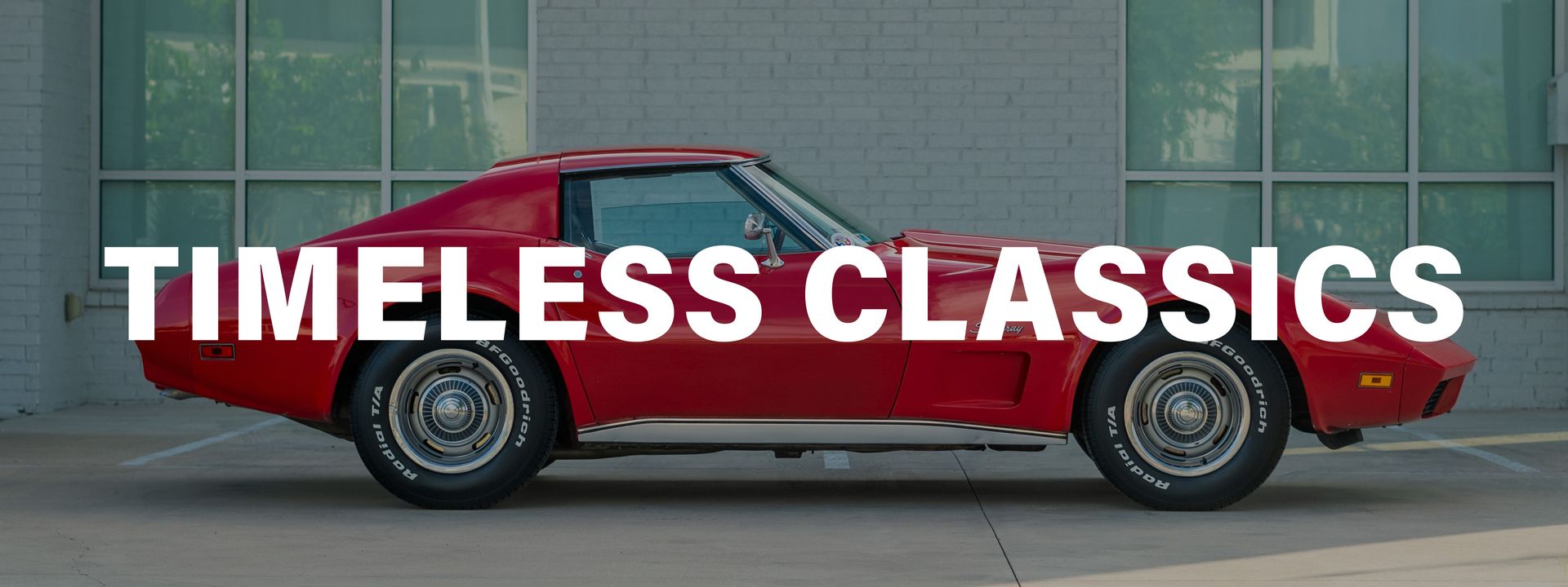 A red car is parked in front of a building with the words timeless classics above it.