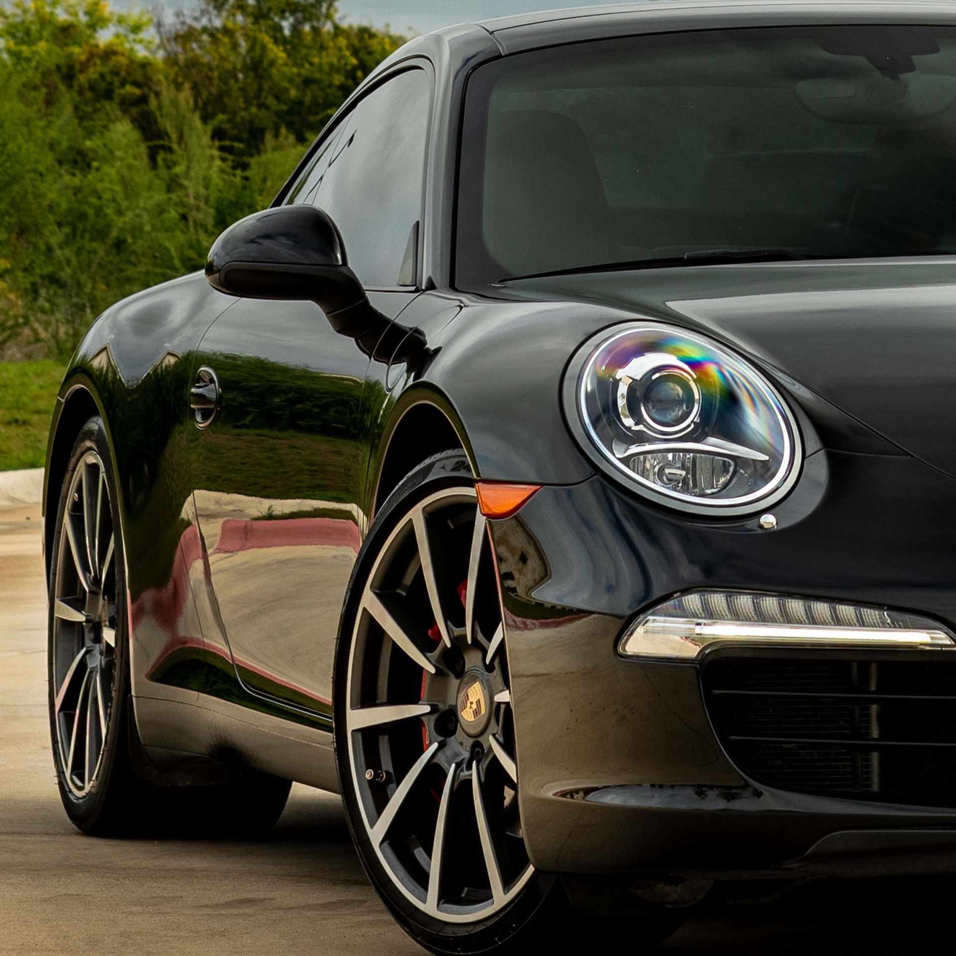 A black porsche 911 is parked in a parking lot