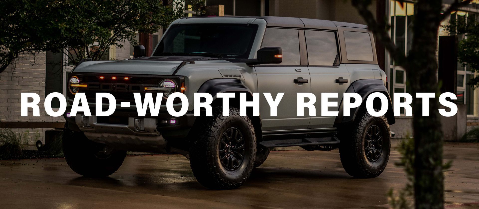 A gray jeep is parked in front of a building.