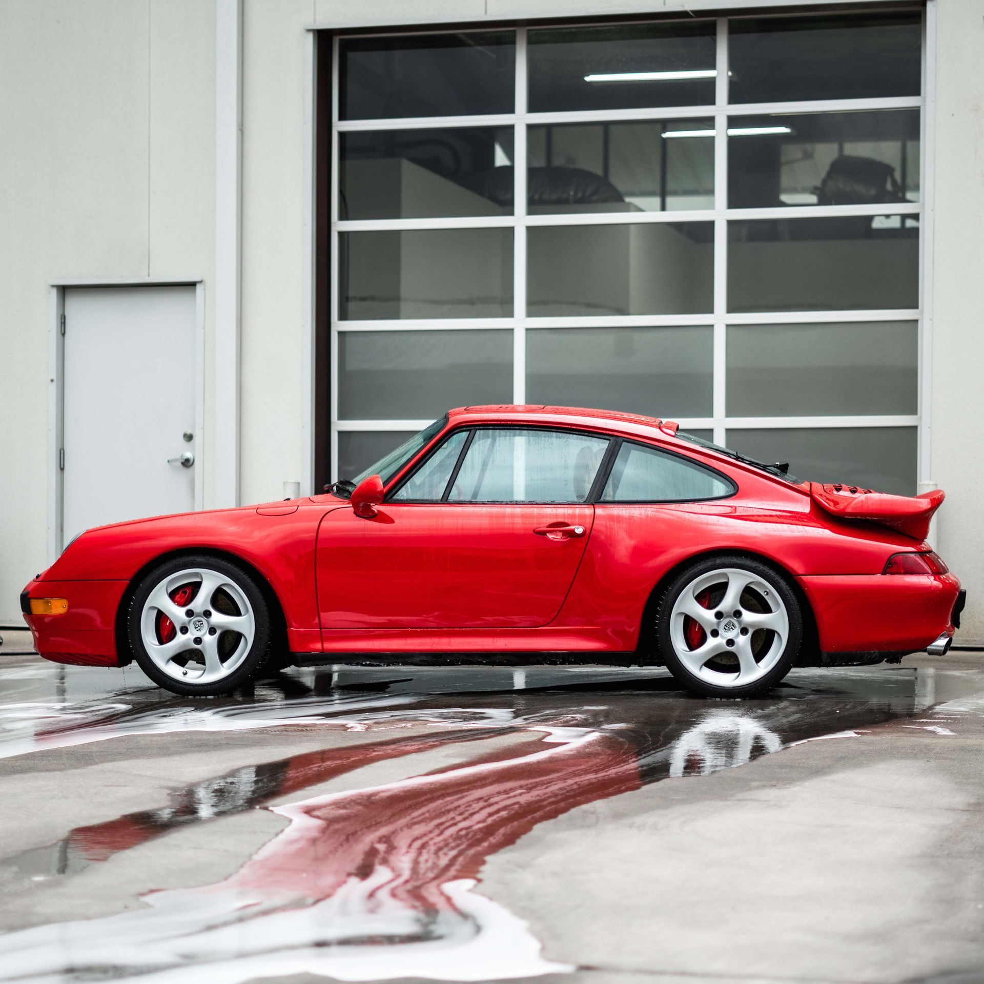 A red car is parked in front of a garage door